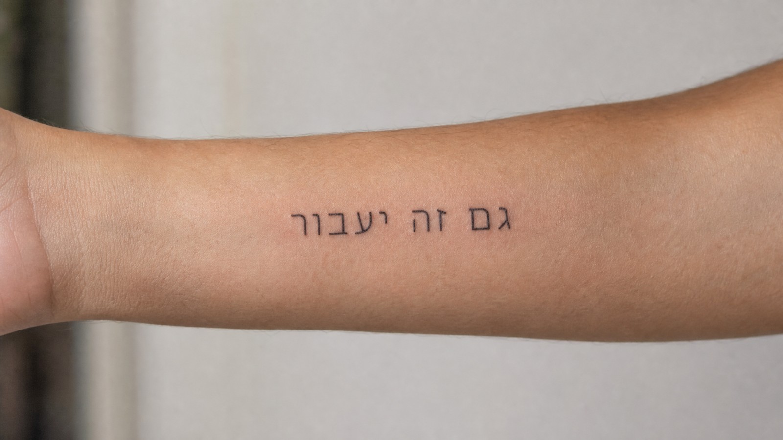 קעקוע בעברית על האמה, גם זה יעבור, בקו דק